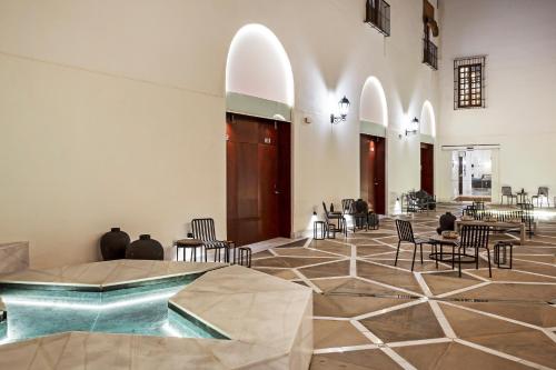 a lobby with chairs and tables and a pool at One Shot Conde Torrejón in Seville
