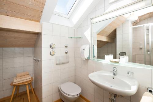 a white bathroom with a sink and a toilet at Landhaus Kössel in Füssen