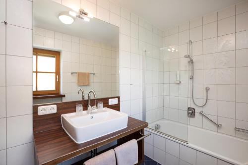 a white bathroom with a sink and a shower at Landhaus Kössel in Füssen
