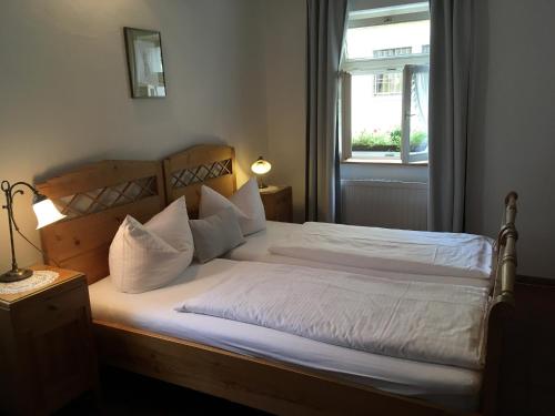 1 dormitorio con 1 cama grande con sábanas blancas y ventana en Weingärtner's Hof, en Sommerach