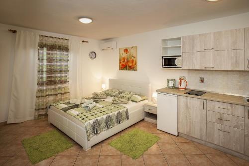 a bedroom with a large bed and a kitchen at Apartments Juranic I in Baška