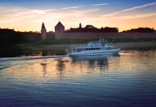 a boat on the water with a castle in the background at AMAKS Russia Hotel in Velikiy Novgorod