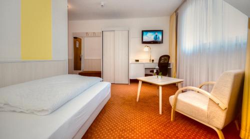 ユルツェンにあるCityHotel Uelzenのベッドとテーブルが備わるホテルルームです。