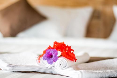 a white towel with flowers on a bed at Sitala Villa in Ubud