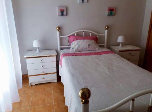 ein Schlafzimmer mit einem weißen Bett und zwei Nachttischen in der Unterkunft Apartamento da Praia da Amorosa in Amorosa