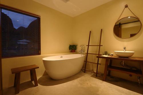 a bathroom with a large tub and a sink at Yangshuo Yulong River Vision Villa in Yangshuo