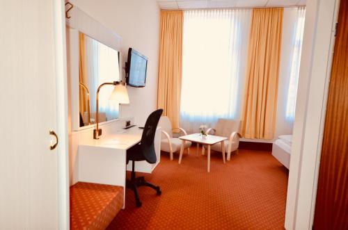 a hotel room with a desk and a bedroom at CityHotel Uelzen in Uelzen