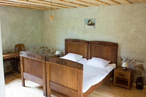 Un dormitorio con una gran cama de madera con sábanas blancas. en Lauku māja "Zvejnieki", en Ķegums