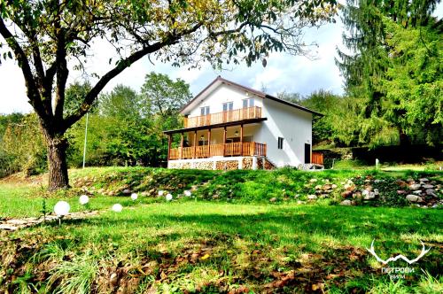 a house on a grassy hill with a tree at Пе́трови Вили in Ribarica