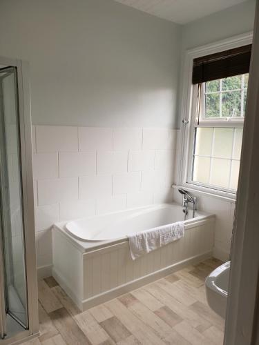 a white bathroom with a tub and a window at The Red Lion in Kilsby
