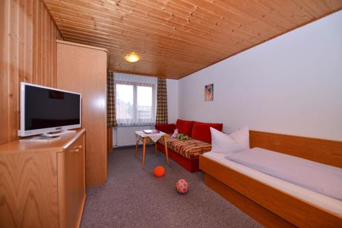 a living room with a couch and a tv in a room at Hotel Landhaus Schmid in Fischen