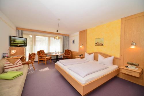 a hotel room with a large bed and a couch at Hotel Landhaus Schmid in Fischen