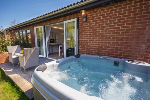 a hot tub in front of a brick house at The Lakes Rookley in Rookley