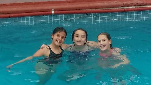 three girls swimming in a swimming pool at Palmas del Lago in Villa Carlos Paz