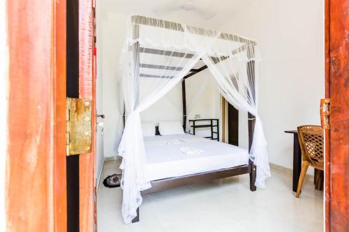 a bedroom with a bed with a mosquito net at Cocoplant Surf Inn in Midigama