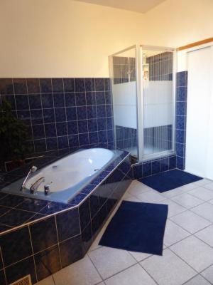 La salle de bains est pourvue de carrelage bleu, d'une baignoire et d'une douche. dans l'établissement La Mimona, à Sainte-Eulalie-en-Born