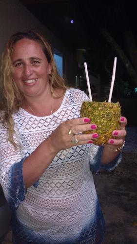 a woman is holding a pineapple in her hands at Vila Alegria in Bombinhas