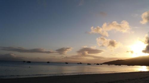 a sunset on the beach with boats in the water at Vila Alegria in Bombinhas