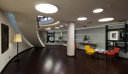 a lobby with chairs and tables and a staircase at Pestana Porto - A Brasileira, City Center & Heritage Building in Porto