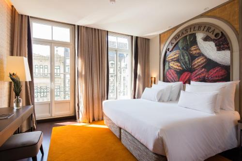 a hotel room with a large bed and a large window at Pestana Porto - A Brasileira, City Center & Heritage Building in Porto