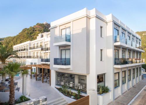 an exterior view of a white building with palm trees at Samian Mare Hotel, Suites & Spa in Karlovasi