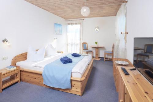 a bedroom with a large bed and a television at Zur Glashütte Landpension in Fabrikschleichach