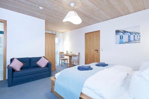 ein Schlafzimmer mit einem Bett und einem blauen Sofa in der Unterkunft Zur Glashütte in Fabrikschleichach