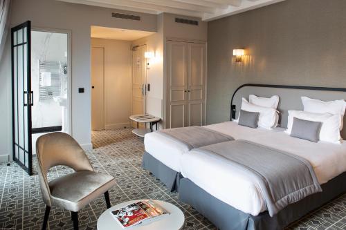 a hotel room with a large bed and a chair at Lenox Montparnasse in Paris