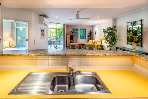 a kitchen with a sink and a living room at Palm Cove Holiday Apartment in Palm Cove