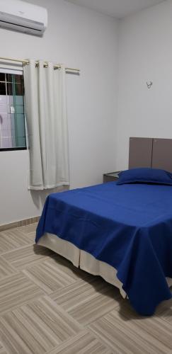 Un dormitorio con una cama azul y una ventana en CONDOMÍNIO VENTO DO LITORAL, en Luís Correia