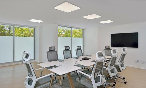 a conference room with a table and chairs and a flat screen tv at INNSiDE by Meliá Calviá Beach in Magaluf