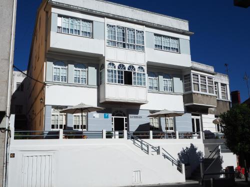 a white building with umbrellas in front of it at Hotel La Terraza in Miño