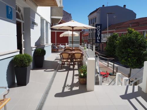 an outdoor patio with chairs and an umbrella at Hotel La Terraza in Miño
