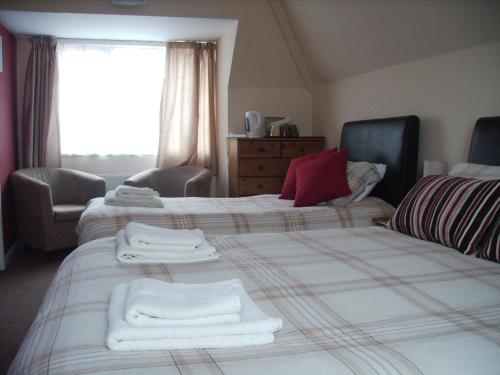 a bedroom with two beds with white towels on them at Singlecote in Skegness