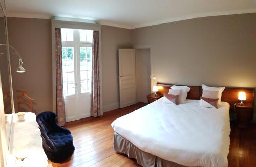 une chambre avec un grand lit blanc et une chaise dans l'établissement Manoir du Chambellan, à Arnières-sur-Iton