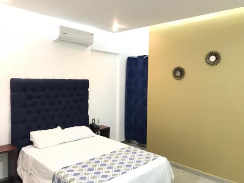 a bedroom with a bed with a black headboard at Hotel Plaza Amalia in Tuxtla Gutiérrez