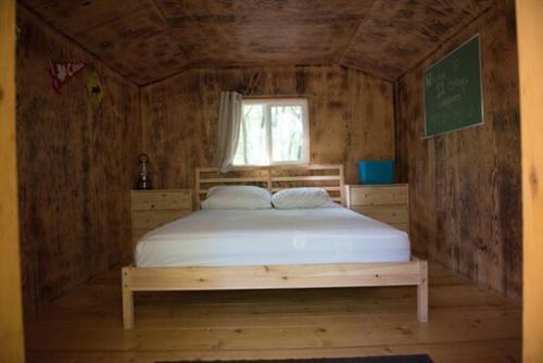 a bed in a wooden room with a window at 11 Bridges Campground and Cabin Park in Rosedale