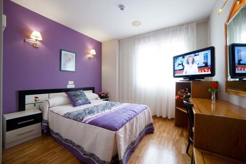 a purple bedroom with a bed and a tv at Hotel Río Cabia in Cabia