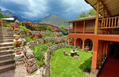 un jardín con una pared de piedra y una casa en Luna Rumi Hotel-Lodge Urubamba, en Urubamba