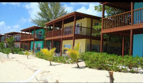 a building on the beach with palm trees in front at The Sands Hotel in Cockburn Town