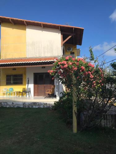 a house with a plant with red flowers in front of it at Pousada Res. Belmont in Pirangi do Norte