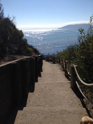 a dirt path next to a fence and the ocean at The Cliffs Hotel and Spa in Pismo Beach