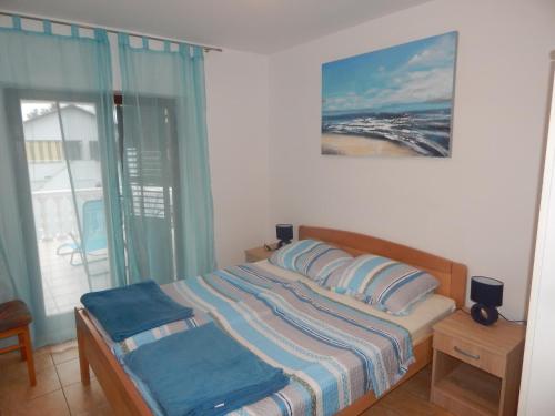 ein Schlafzimmer mit einem Bett mit blauen Kissen und einem Fenster in der Unterkunft Apartmani Nin in Nin