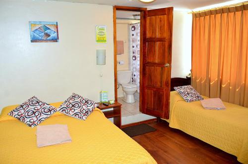 a room with two beds and a bathroom at Hostal Terra 4 - EL LABRADOR in Quito