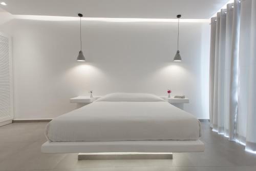 a white bedroom with a white bed and two lights at Aeolos Resort in Mýkonos City