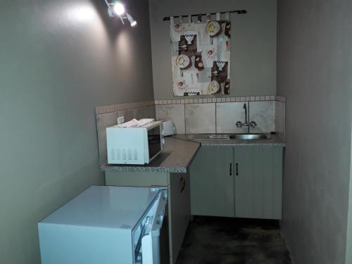 uma pequena cozinha com um micro-ondas e um lavatório em Charilo em Dullstroom