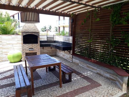 eine Terrasse mit einem Holztisch und einem Kamin in der Unterkunft Apartamento Taíba Beach Resort in Taíba