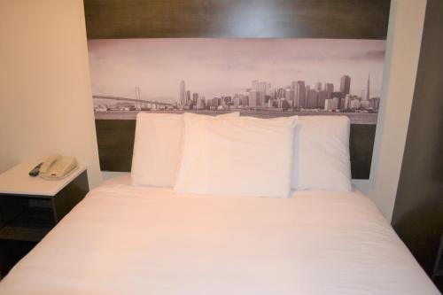 un letto con cuscini bianchi in una camera con vista sullo skyline della città di Inn on Folsom a San Francisco