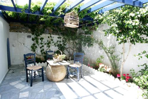 un patio con mesa y sillas bajo una pérgola en Studios Eleni I, en Tinos