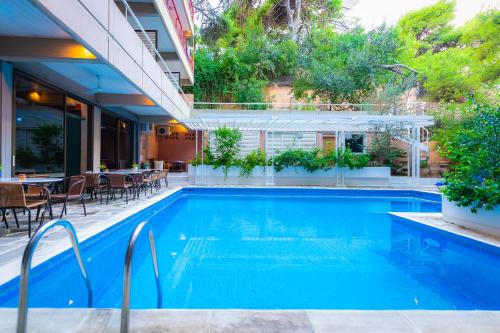 a swimming pool with tables and chairs next to a building at Apollonia Hotel Apartments in Varkiza
